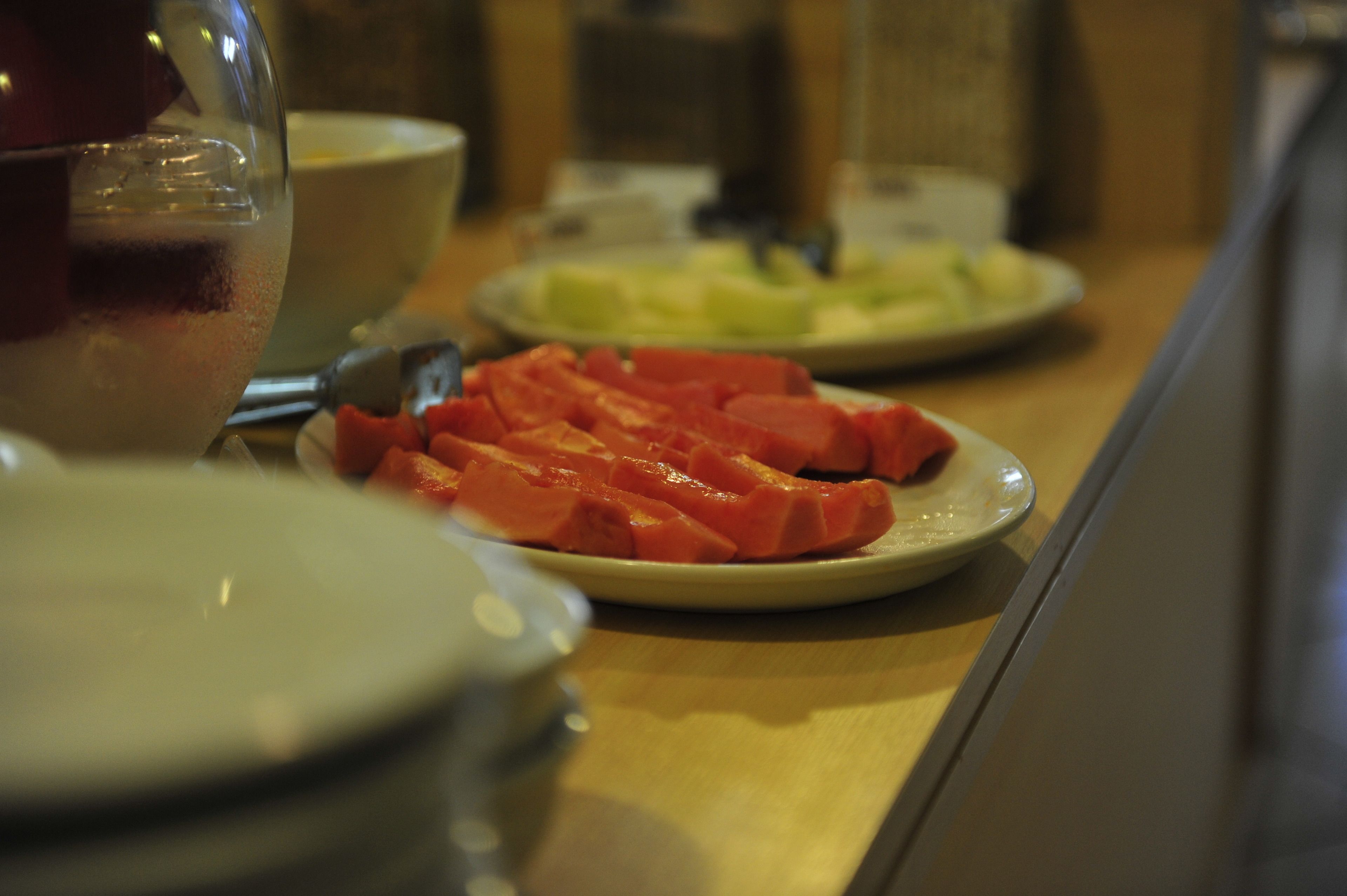 Una mesa de comedor con platos de comida, incluyendo rodajas de tomate y un vaso de bebida roja.