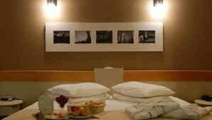 A hotel room with a neatly made bed, a wall-mounted photo display, and a breakfast tray on the nightstand. - Bergson Flat (Caxias do Sul)