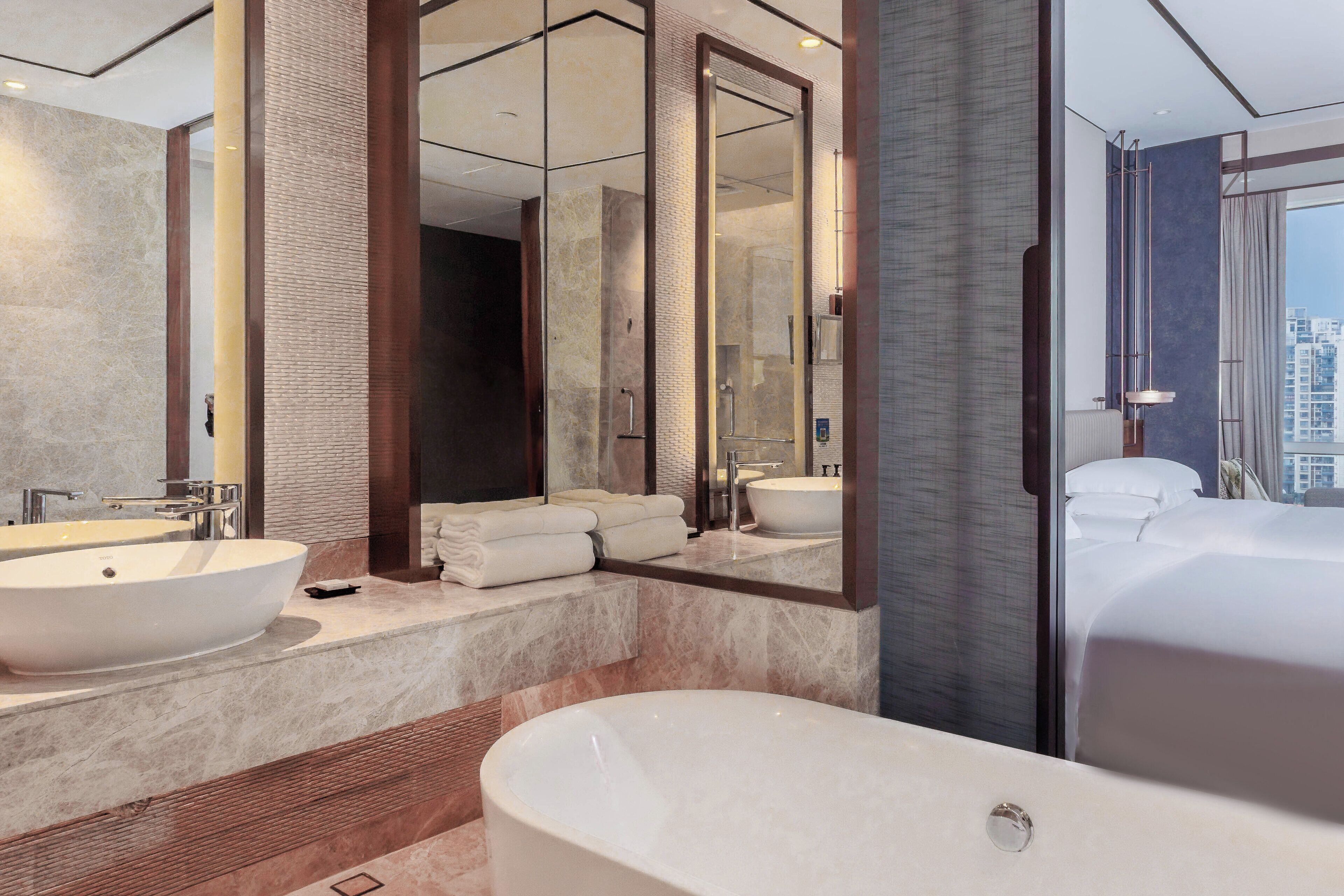 A modern bathroom with a large bathtub, two sinks, and a large mirror.