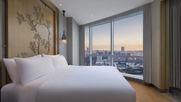 A modern hotel room with a large bed, a city view, and a decorative wall.