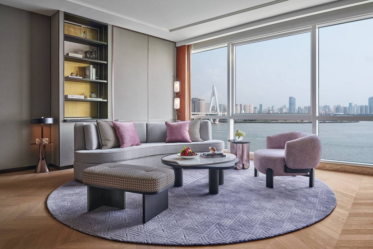 A modern living room with a large window, a sofa, a coffee table, and a side table.