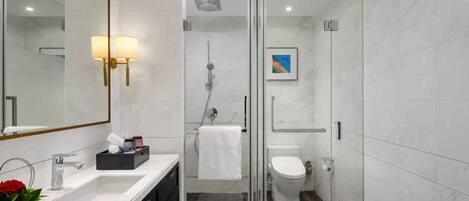 A modern bathroom with a glass-enclosed shower, a white sink with a marble countertop, and a large mirror.