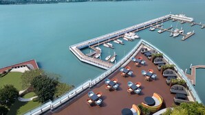 A marina with boats docked, a deck with outdoor seating, and a city skyline in the background. - InterContinental Haikou Seaview by IHG (Haikou)