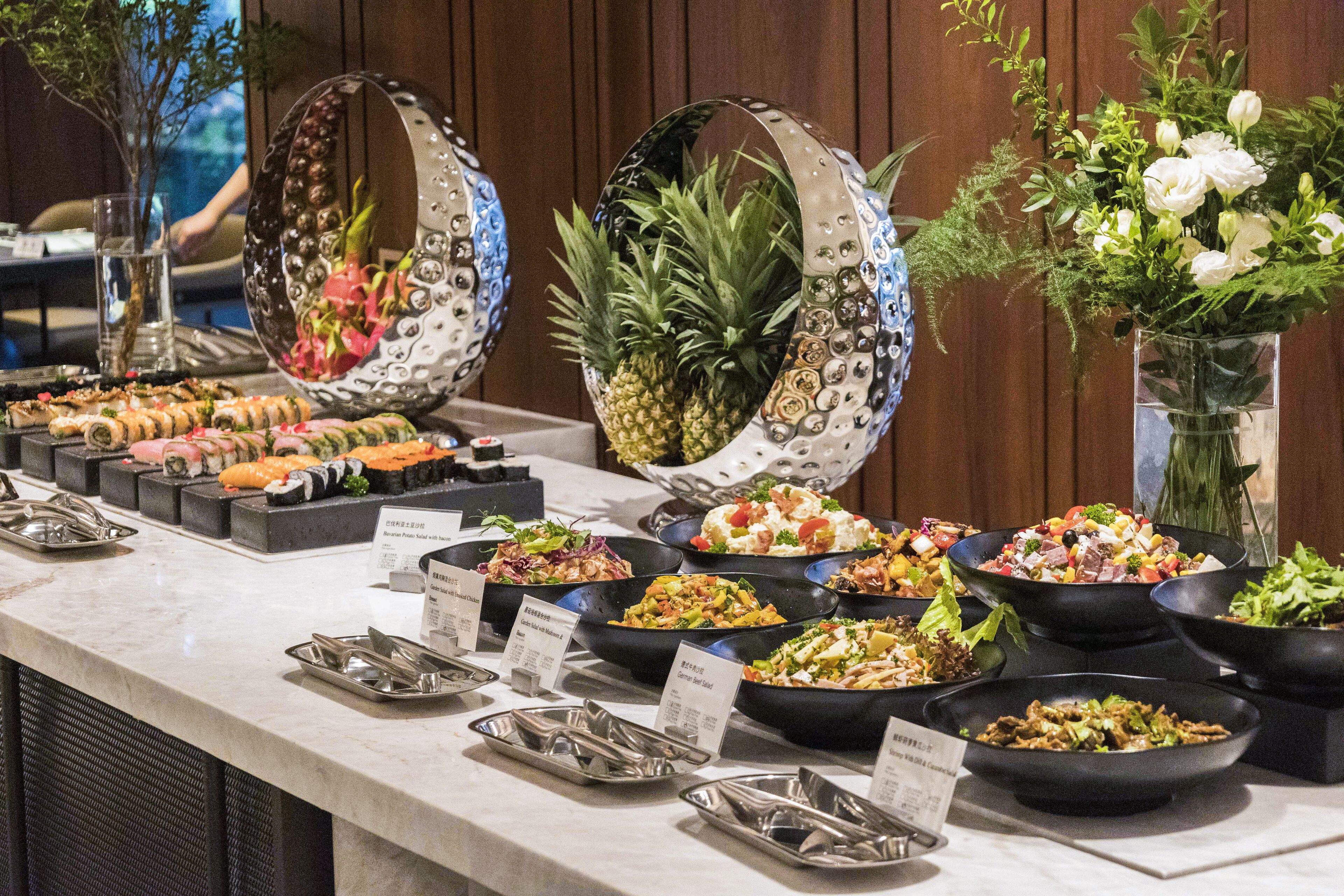 Un buffet proposant divers plats, agrémenté d’un ananas décoratif en guise de centre de table.