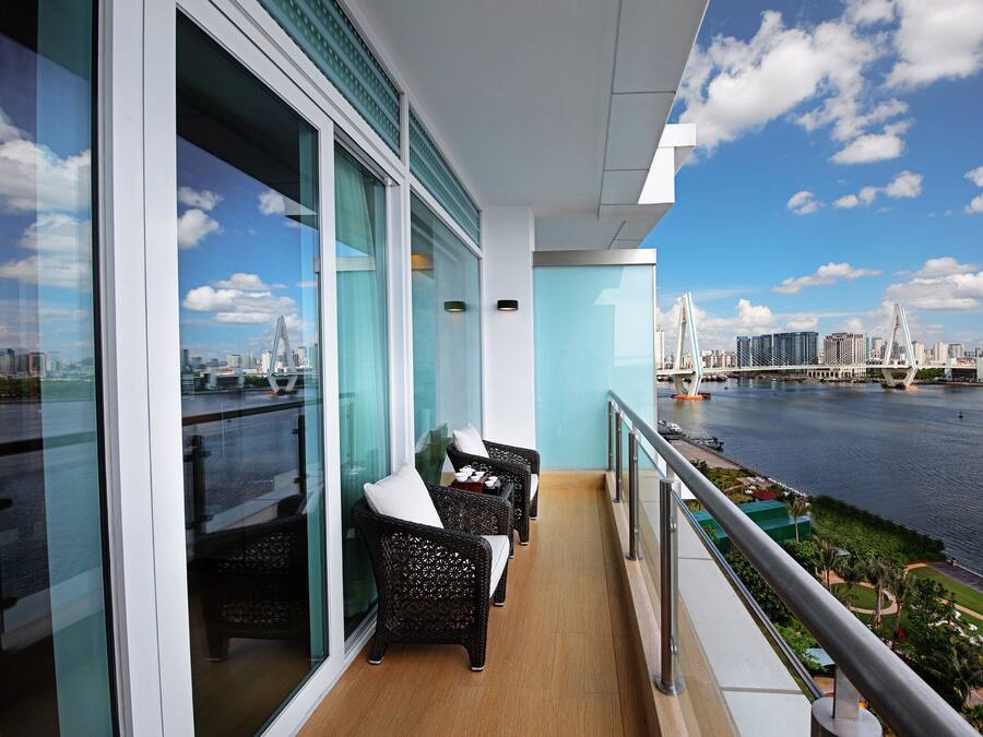 Un balcone con mobili in vimini e vista sullo skyline cittadino e un ponte sull'acqua.