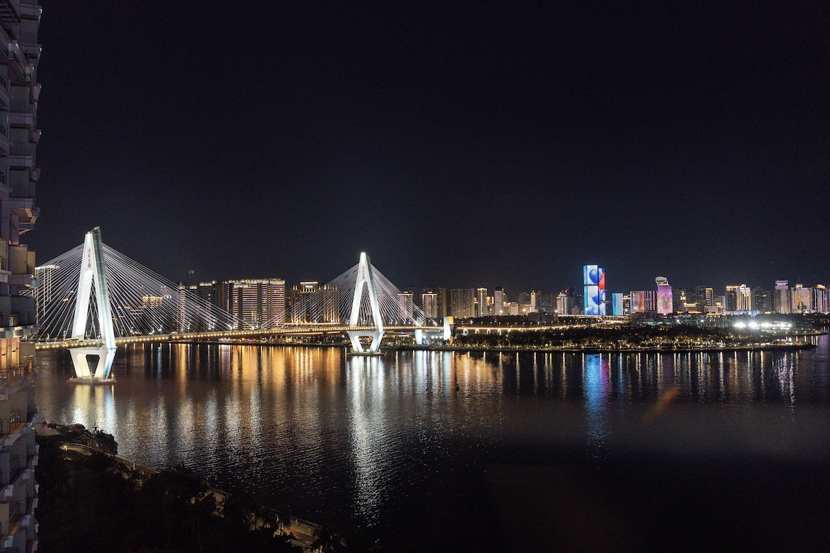 Un paisaje urbano nocturno con un puente destacado y edificios iluminados.