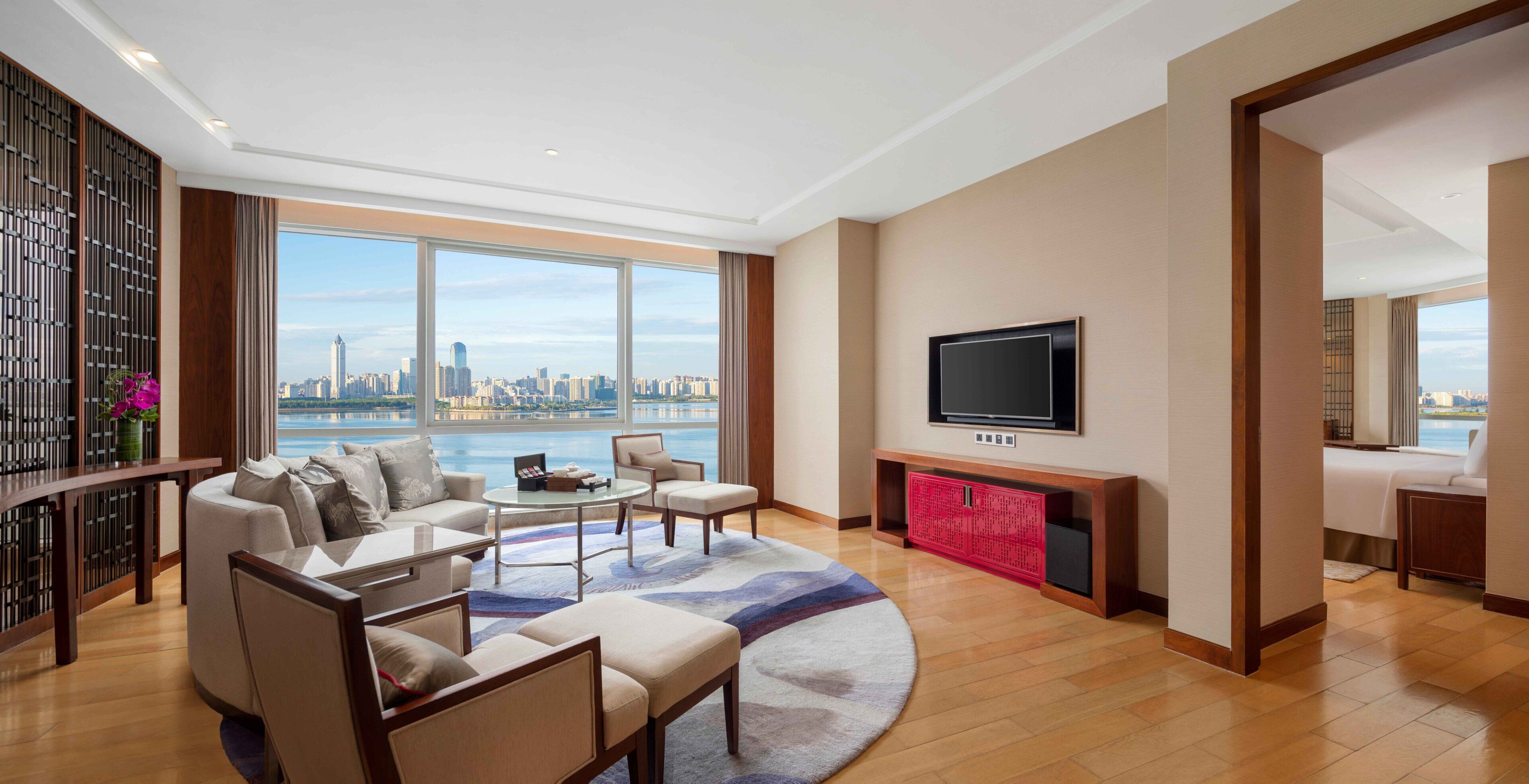 A modern living room with a city view, a flat-screen TV, and a seating area.