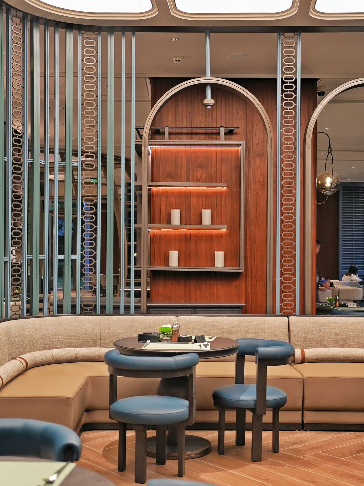 A modern interior with a curved sofa, two chairs, a small table, and a wooden wall with shelves.