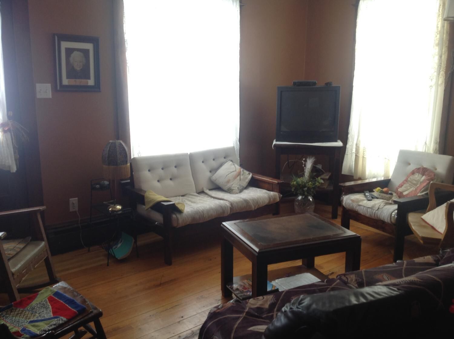 A living room with a sofa, armchairs, a coffee table, a television, and a lamp.