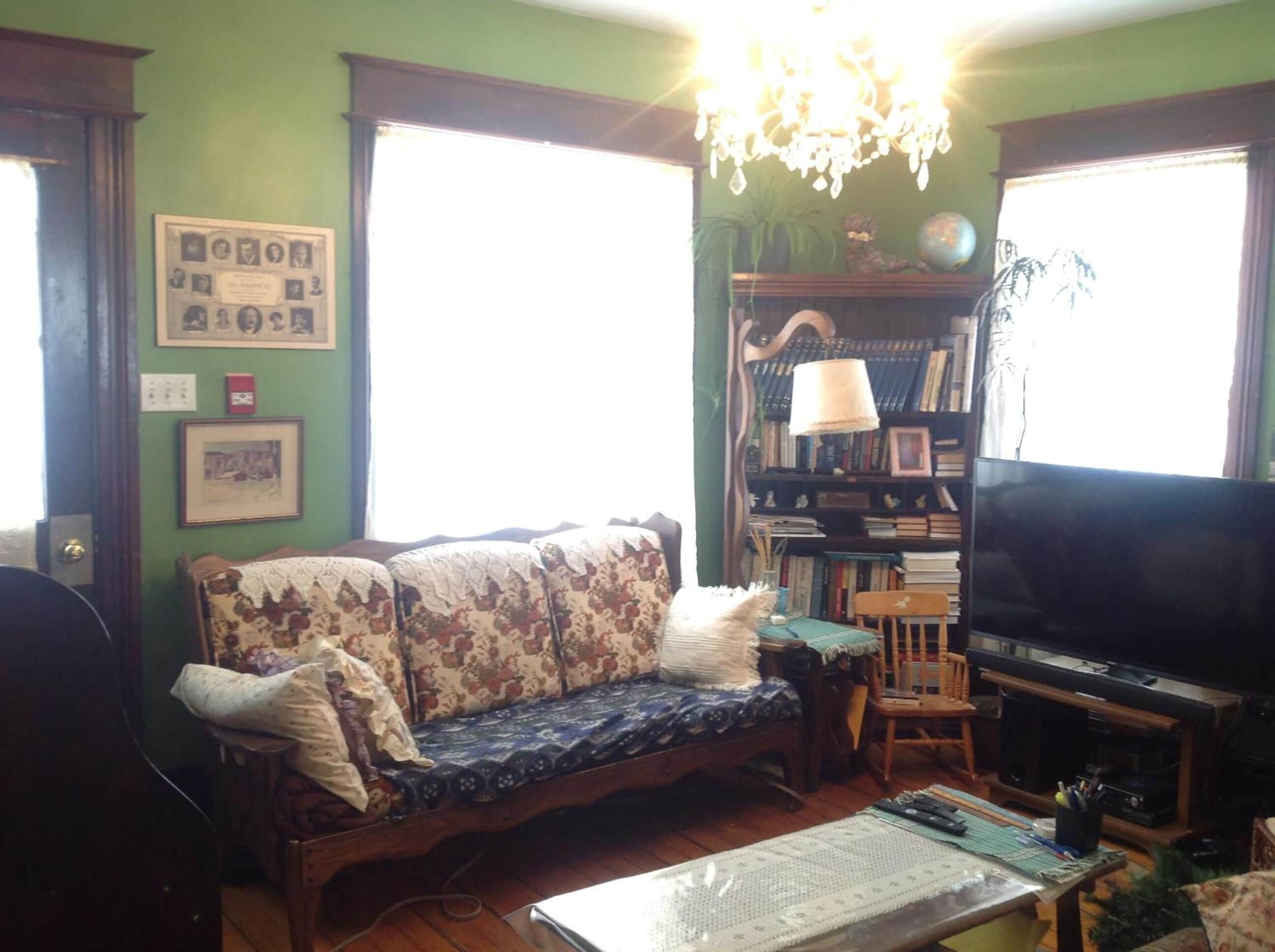 Una sala de estar con sofá, televisión, estantería y candelabro.