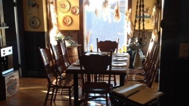 A dining area with wooden chairs and a table, a ceiling fan, and a window with a view of the sky.