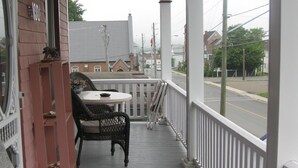 A covered porch with a table and chairs, a brick wall, and a view of the street.