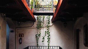Una escalera con barandilla de hierro forjado, un extintor y un letrero que indica una salida.