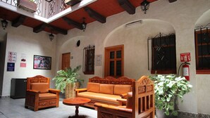 Un interior tradicional con un sofá de madera, dos sillones, una mesita y una planta en maceta.