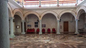 Un interior con suelo a cuadros, techos abovedados y asientos rojos.