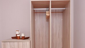 A walk-in closet with a wooden finish, a hanging rod, and a small table with cups and a mug.