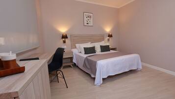 Un dormitorio ordenado con cama, mesitas de noche, escritorio y una silla.