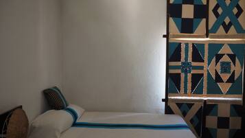 Een kamer met een bed, kussens en een wand met behang.