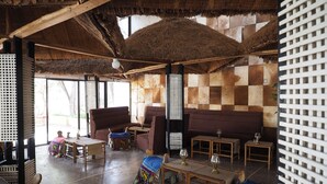 Interior rústico com tetos de palha, móveis de madeira e padrão de parede xadrez.