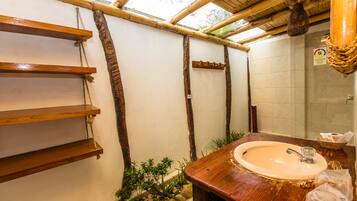 A bathroom with a wooden vanity, a sink, and a small plant area.