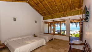 Una habitación con dos camas, televisión y vista a la playa.