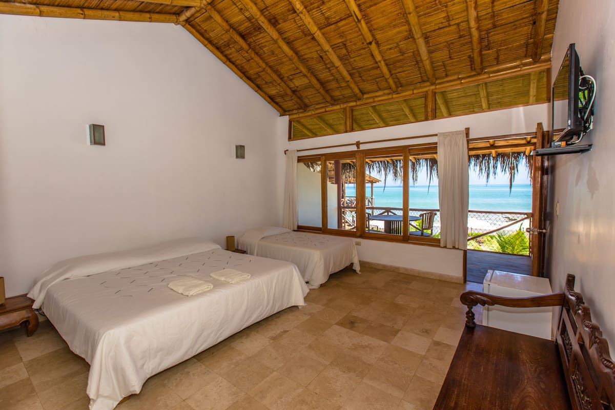 Una habitación con dos camas, televisión y vista a la playa.