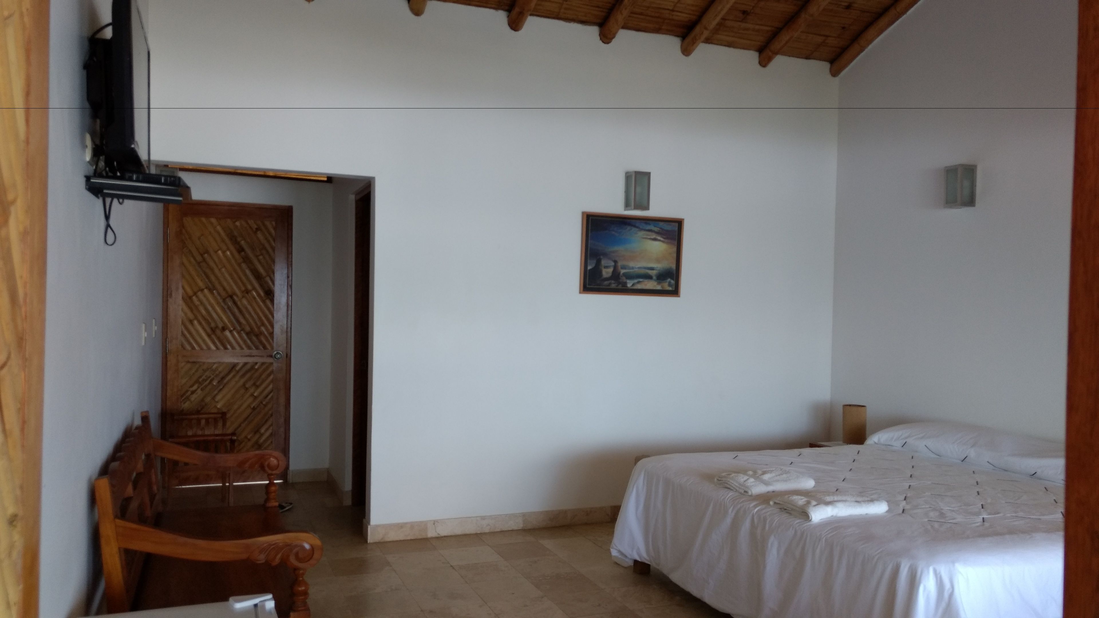 A room with a bed, a chair, a painting, and a wooden door.