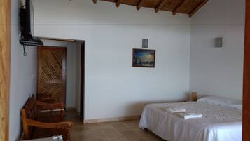 A room with a bed, a chair, a painting, and a wooden door.