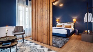 Un dormitorio con cama, lámparas de noche, una silla, una mesita y una mesita de noche.