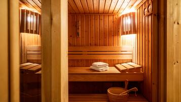 A wooden sauna with benches, a towel, and a wooden bucket.