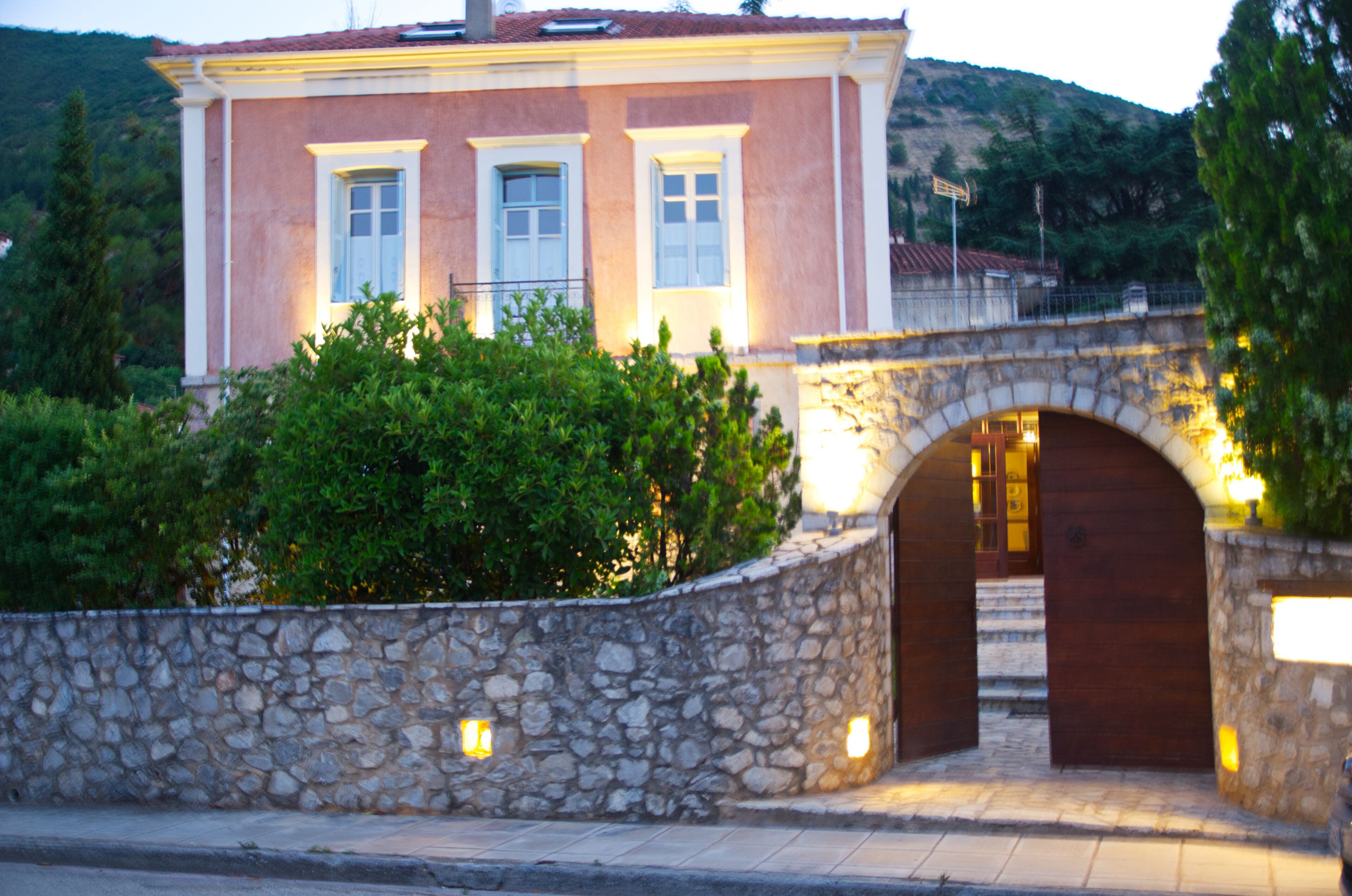 A stone-walled building with a wooden door and a stone bridge in the background.