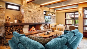 Una sala de estar acogedora con chimenea de piedra, sofás azules y vigas de madera en el techo.