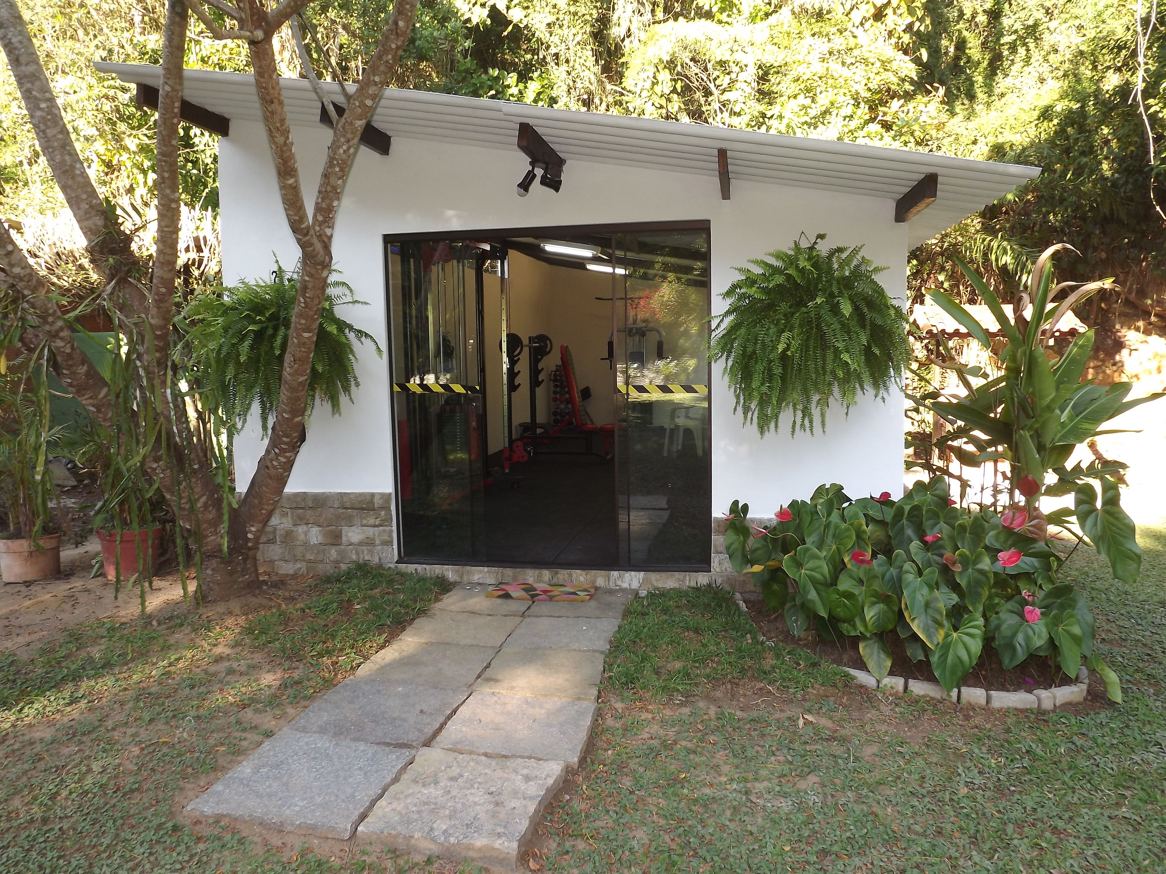 A covered outdoor area with a glass door, surrounded by potted plants and a stone pathway.