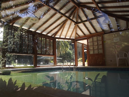 Una piscina techada, una piscina al aire libre, sombrillas