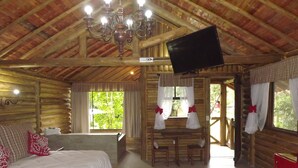 Een slaapkamer in een blokhut met een bed, een bureau en een televisie.