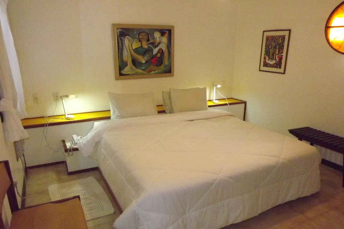 Ein Hotelzimmer mit einem großen Bett, Nachttischlampen, einem Bild an der Wand und einem kleinen Tisch.