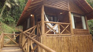 Een houten vakantiehuisje met een veranda en een hangmat.