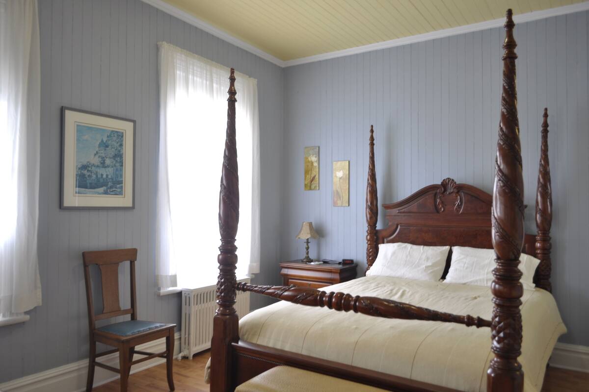 Una cama con dosel en una habitación con paredes azul claro y techo blanco.