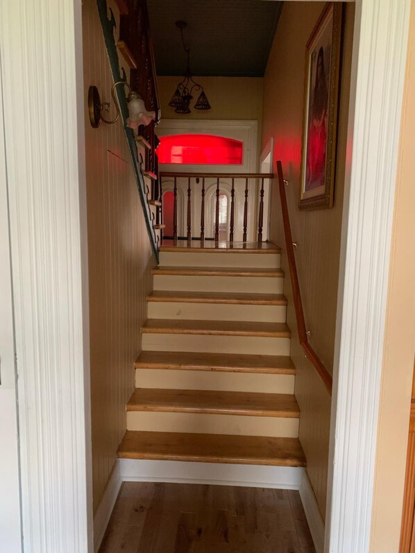 Una escalera de madera con detalles blancos y una pared de acento roja.