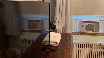 A room with a wooden dresser, a mirror, a radiator, and a window with curtains.