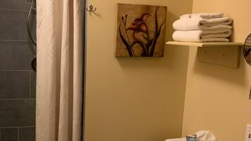 A bathroom with a shower curtain, a toilet, a sink, and a towel rack.