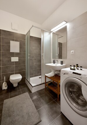 Un baño moderno con ducha, inodoro, lavamanos y lavadora.