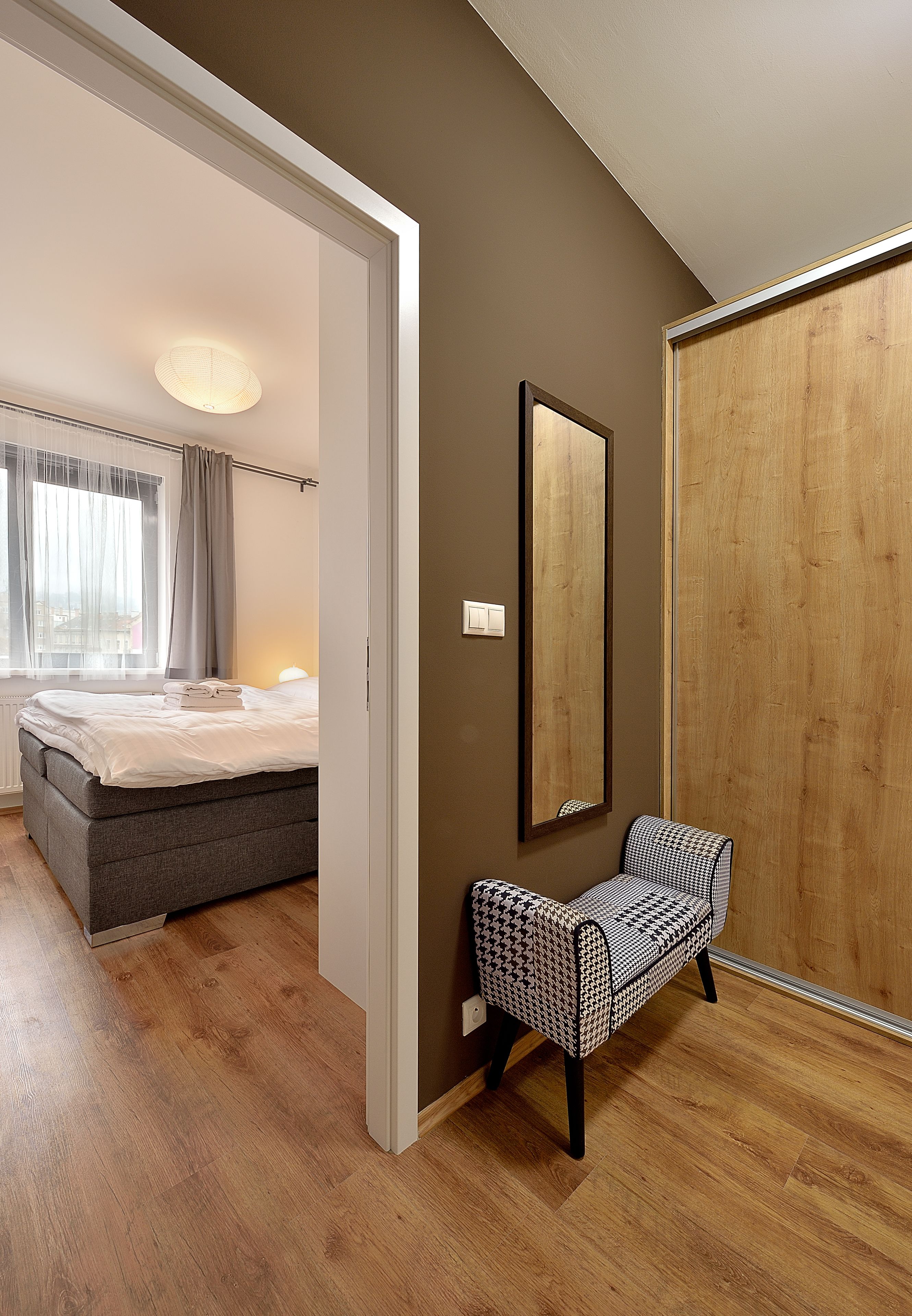 A bedroom with a bed, a bedside table, a mirror, and a wardrobe.