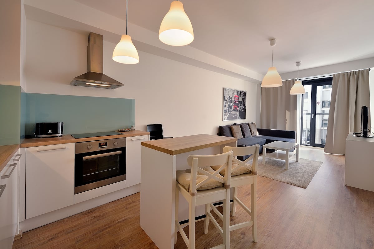 A modern kitchen with a toaster, oven, and a dining area with a table and chairs.
