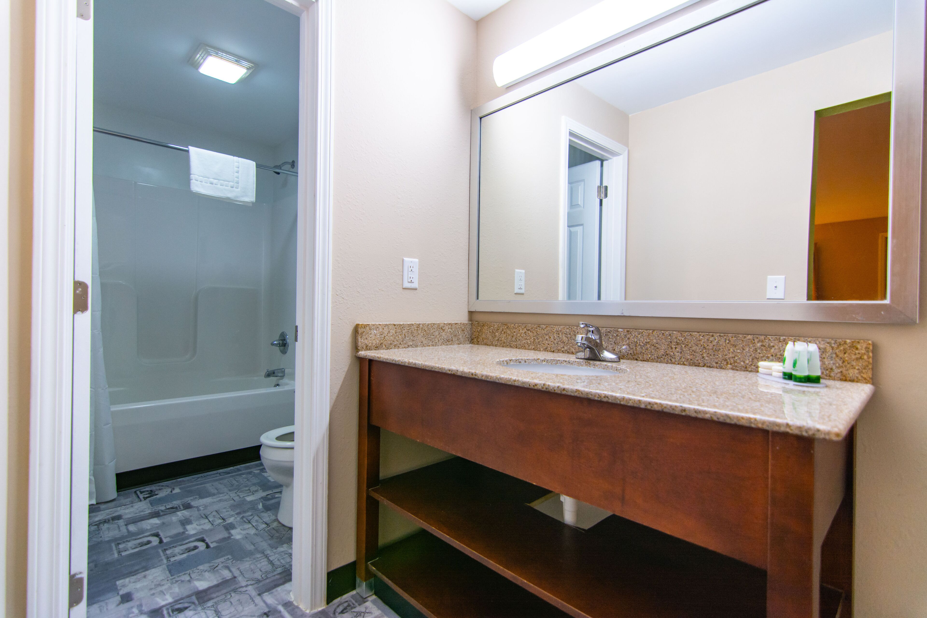 A bathroom with a bathtub, toilet, and a vanity with a mirror.