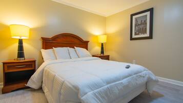 A neatly made bed with white bedding, two bedside lamps, and a framed picture on the wall.