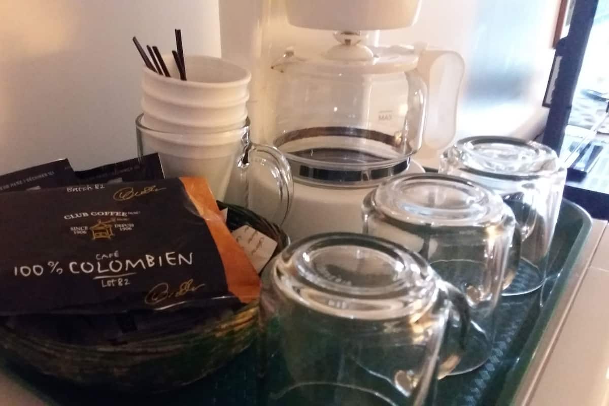 A coffee station with a coffee maker, jars, and coffee packets.