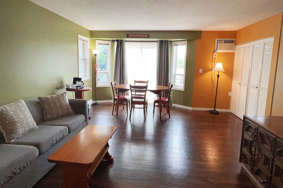 A living room with a sofa, a coffee table, a dining table with chairs, and a lamp.
