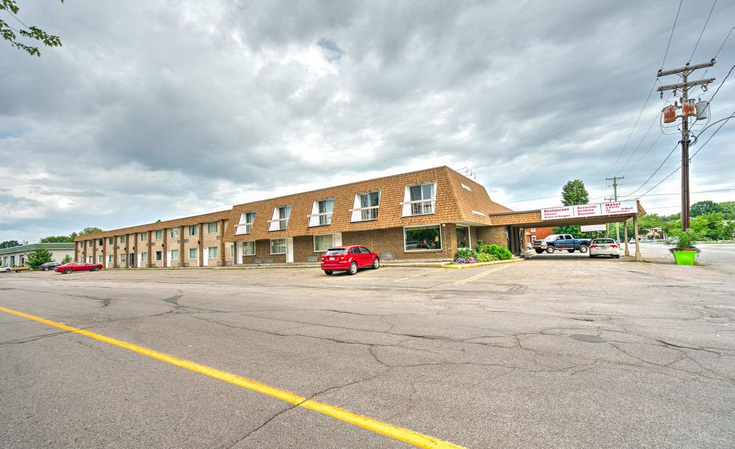 Un motel con una hilera de habitaciones, un estacionamiento y un letrero para restaurante y hotel.