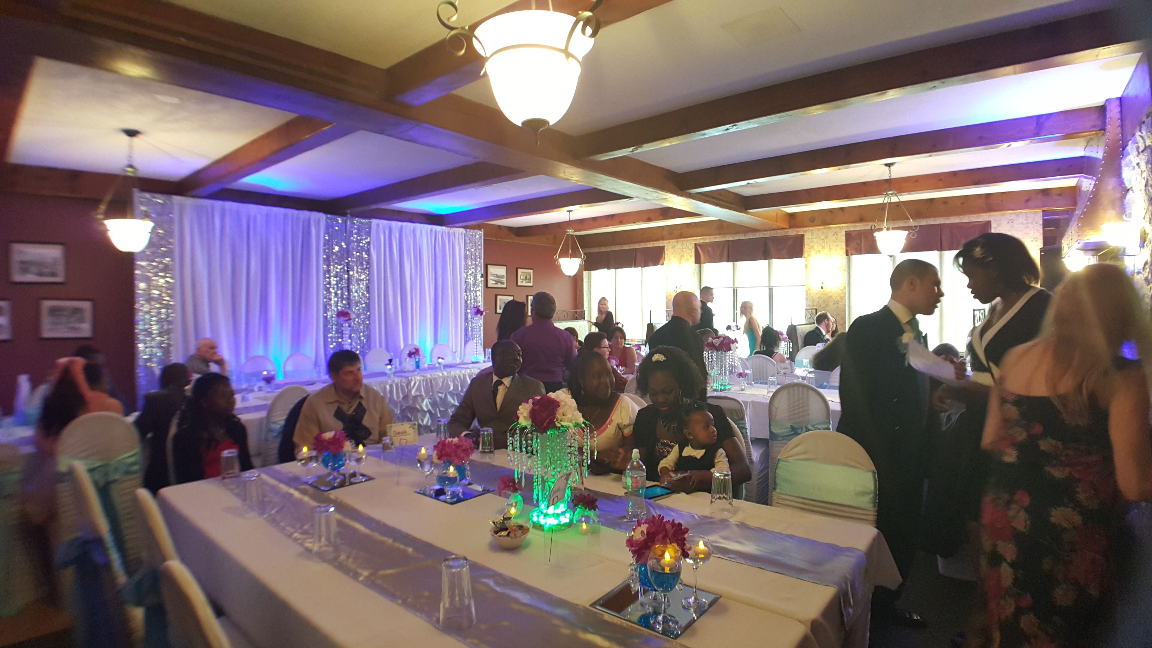 Un gran saló de banquets amb taules preparades per a un esdeveniment formal, amb lluminàries i il·luminació decorativa.